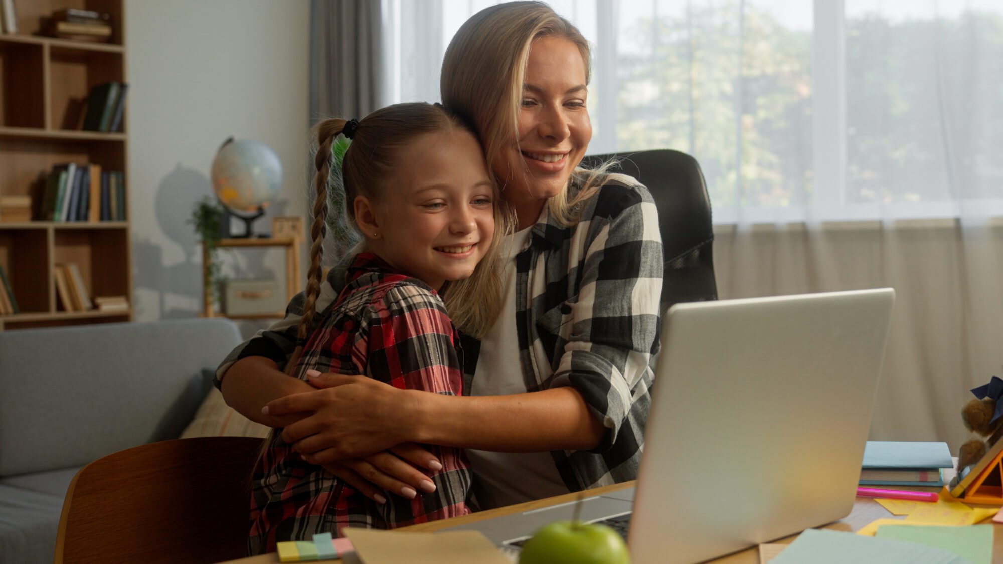 Happy parent mother with daughter child using laptop for school at home